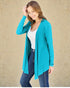 Woman wearing a teal cardigan over a white top and jeans on a beige background