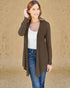 Woman wearing a brown cardigan over a white top and blue jeans against a beige background