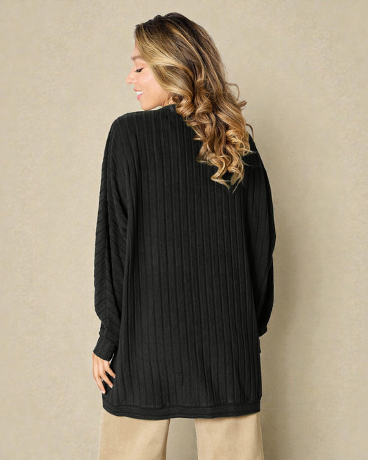 Woman wearing a black ribbed sweater against a beige background