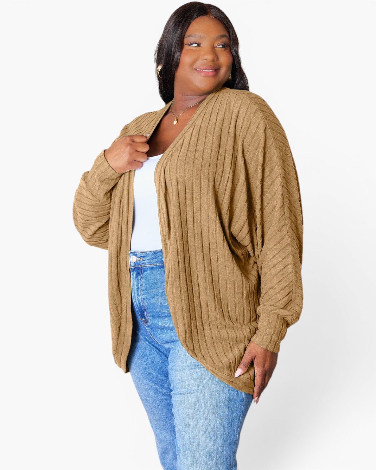 A woman modeling a tan ribbed open-front cardigan over a white top and blue jeans, photographed against a clean white studio background.
