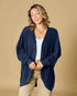 Woman wearing a navy blue cardigan over a white top and beige pants on a beige background