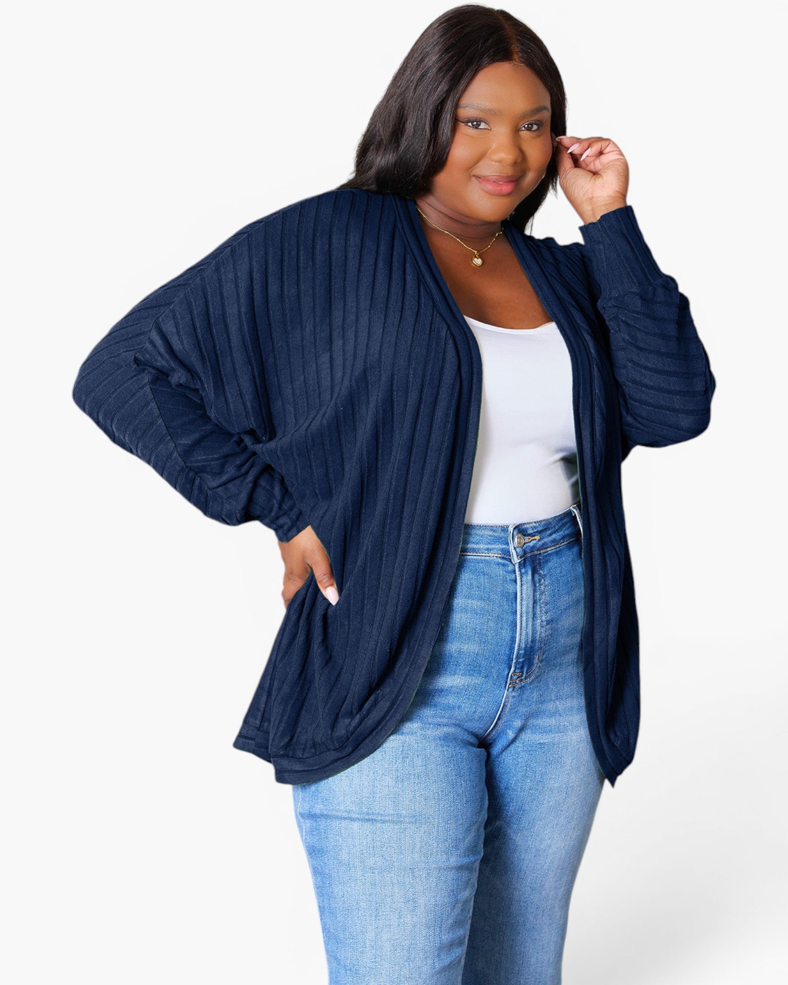 A woman modeling a navy blue ribbed open-front cardigan over a white tank top and blue jeans, photographed against a clean white studio background.