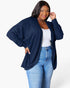 A woman modeling a navy blue ribbed open-front cardigan over a white tank top and blue jeans, photographed against a clean white studio background.