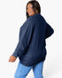 A woman wearing a navy blue ribbed knit long-sleeve top and light blue jeans, photographed against a clean white studio background.