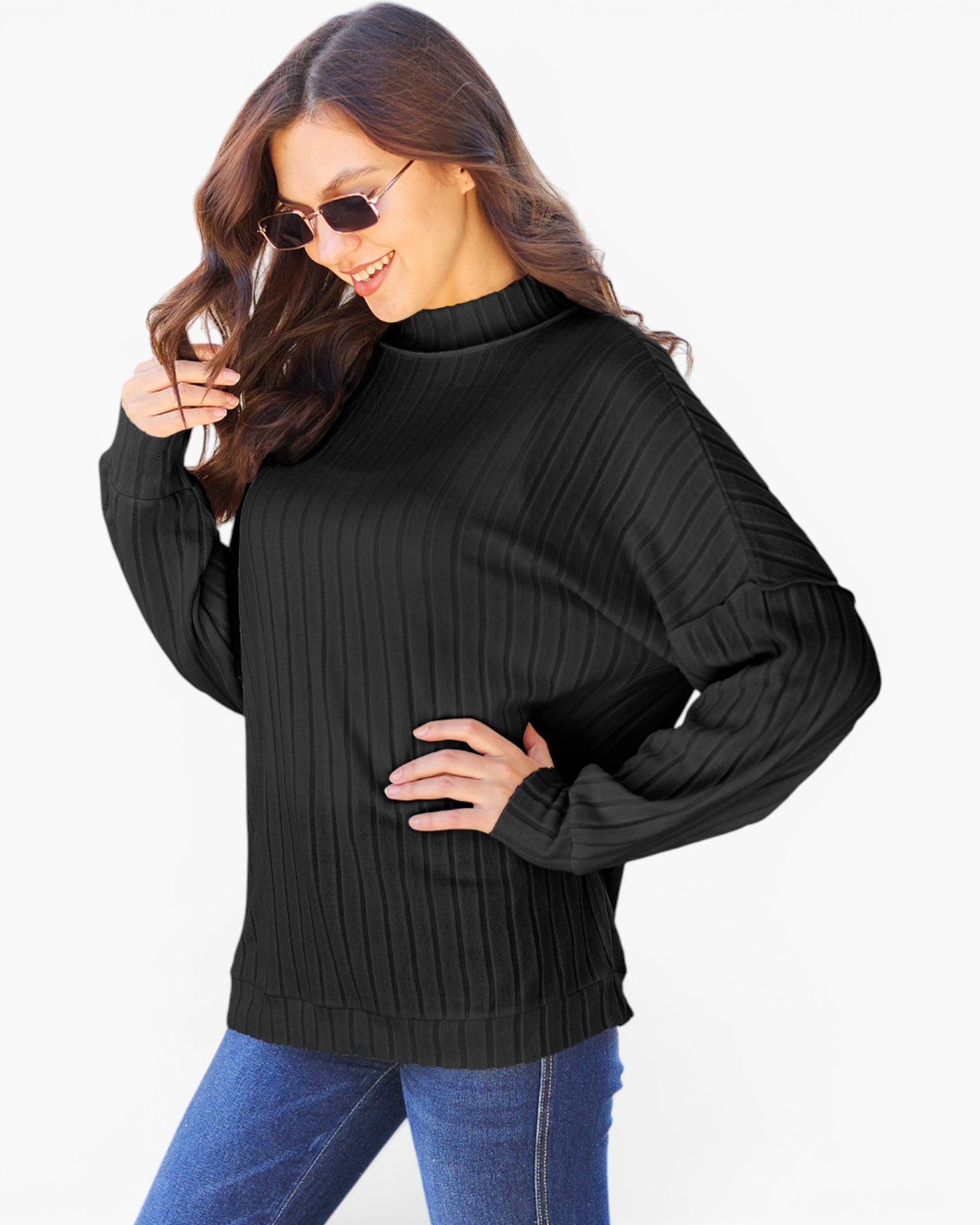 A woman wearing a black ribbed long-sleeve mock neck sweater and blue jeans, posing against a plain white background.