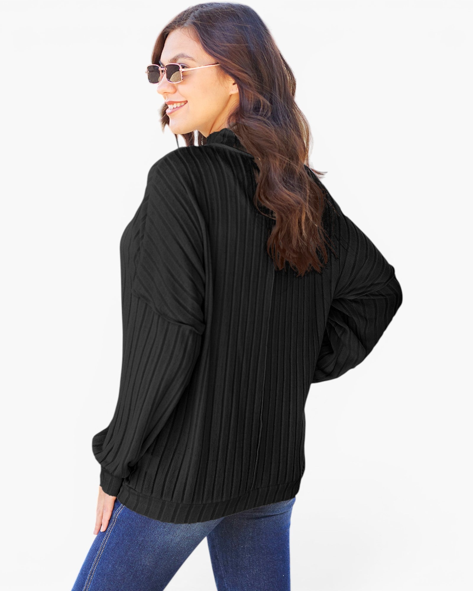 A woman wearing a black ribbed long-sleeve top and blue jeans, photographed from the back against a plain white background.