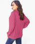 A woman wearing a pink ribbed long-sleeve top and blue jeans, photographed from the back against a plain white background.