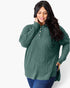 A woman wearing a ribbed knit long-sleeve henley top in sage green with gold buttons, paired with blue jeans, against a plain white studio background.