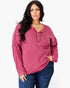A woman modeling a long-sleeve ribbed henley top in a dusty rose pink color, paired with dark blue jeans, against a plain white background.