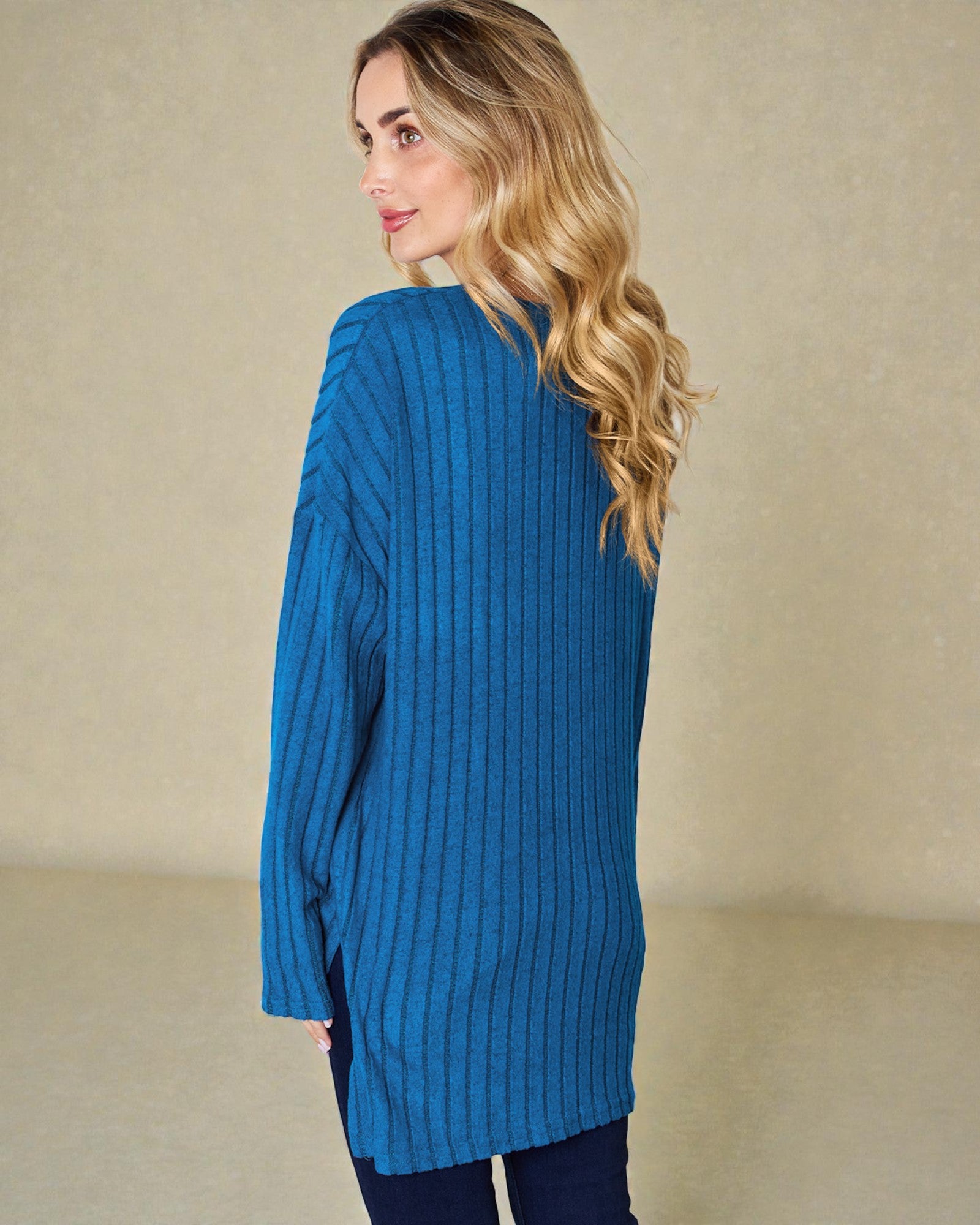 Woman wearing a blue ribbed sweater against a beige background