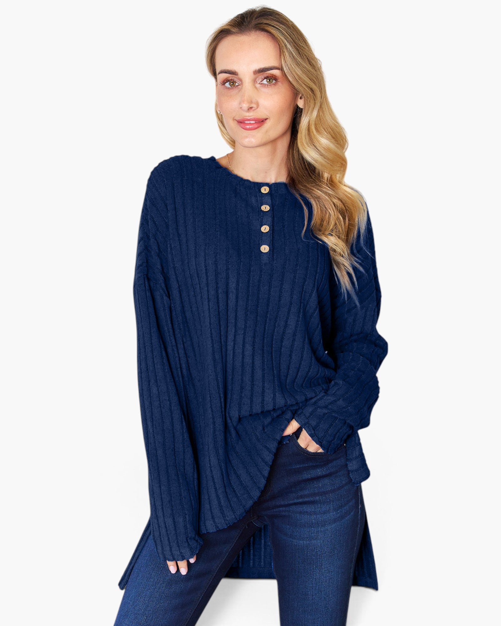 A woman modeling a navy blue ribbed knit long-sleeve top with a buttoned henley neckline, paired with dark blue jeans, against a plain white background.