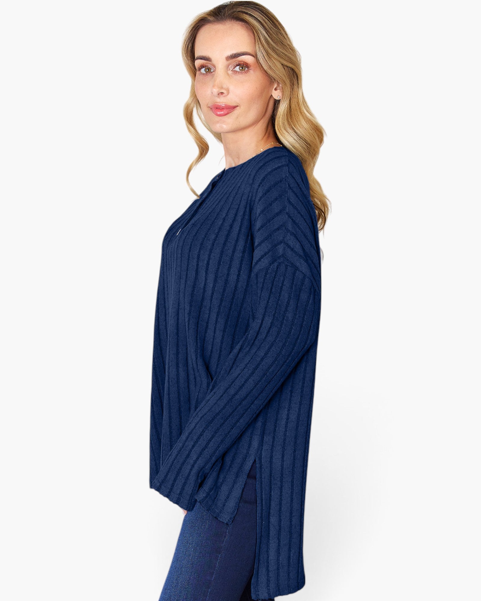A woman modeling a navy blue ribbed knit long-sleeve top against a plain white studio background.
