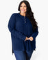 A woman modeling a navy blue ribbed knit long-sleeve tunic top with a three-button henley neckline, paired with blue jeans, against a plain white studio background.