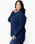 A woman modeling a navy blue ribbed knit long-sleeve top with a buttoned neckline, paired with dark blue jeans, against a plain white studio background.