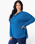 A woman modeling a bright blue ribbed long-sleeve henley top with a buttoned collar, paired with dark blue jeans, against a plain white studio background.