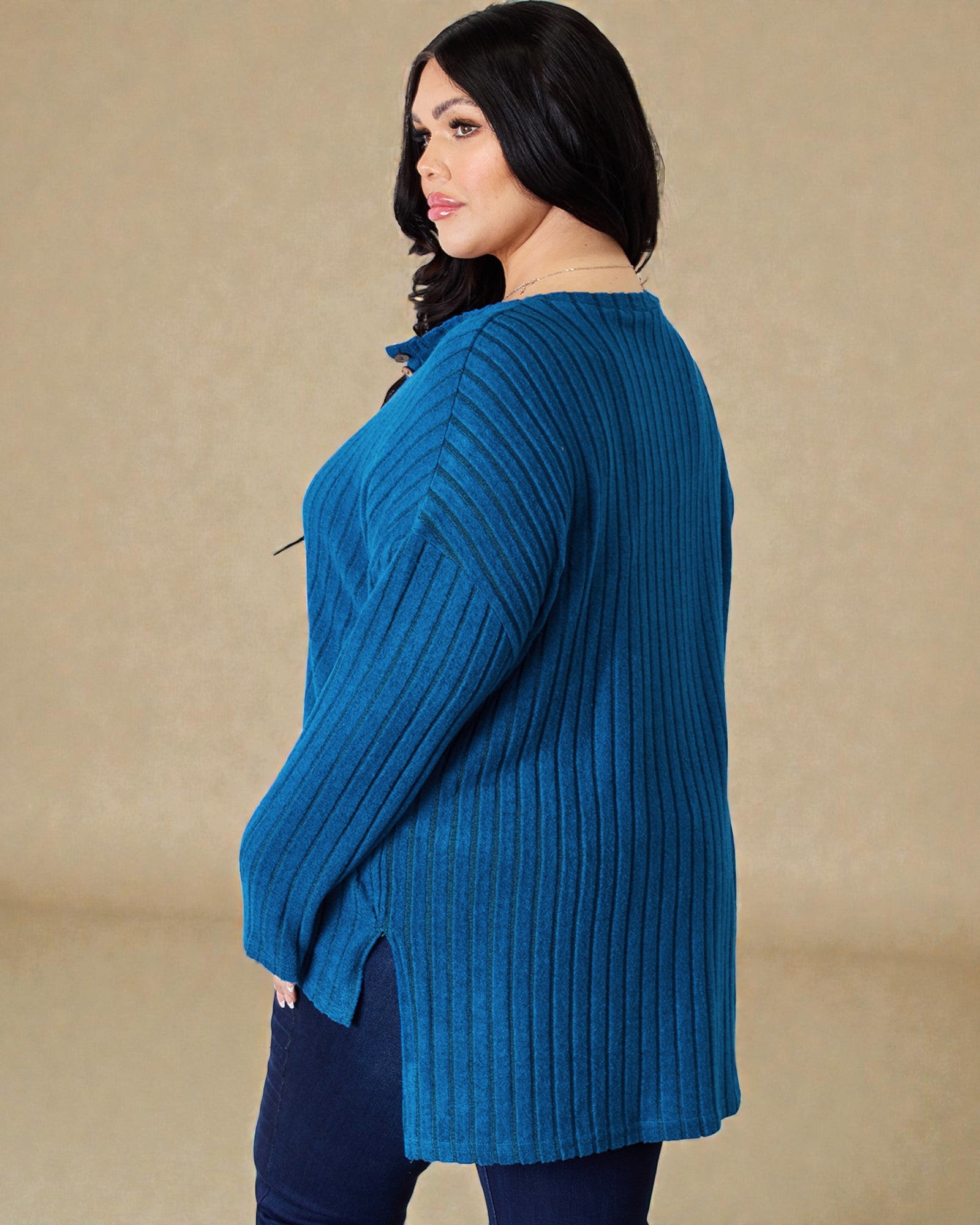 Woman wearing a blue ribbed sweater against a beige background