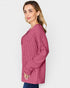 Woman wearing a pink textured long-sleeve shirt against a white background