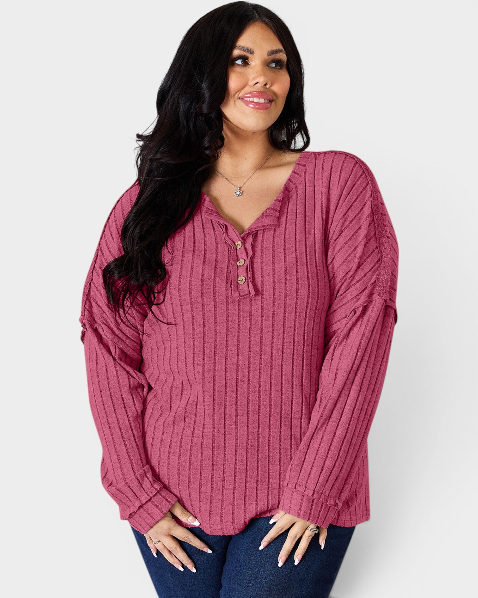 Woman wearing a ribbed pink long-sleeve top against a white background