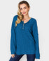 Woman wearing a blue ribbed long-sleeve top on a plain background