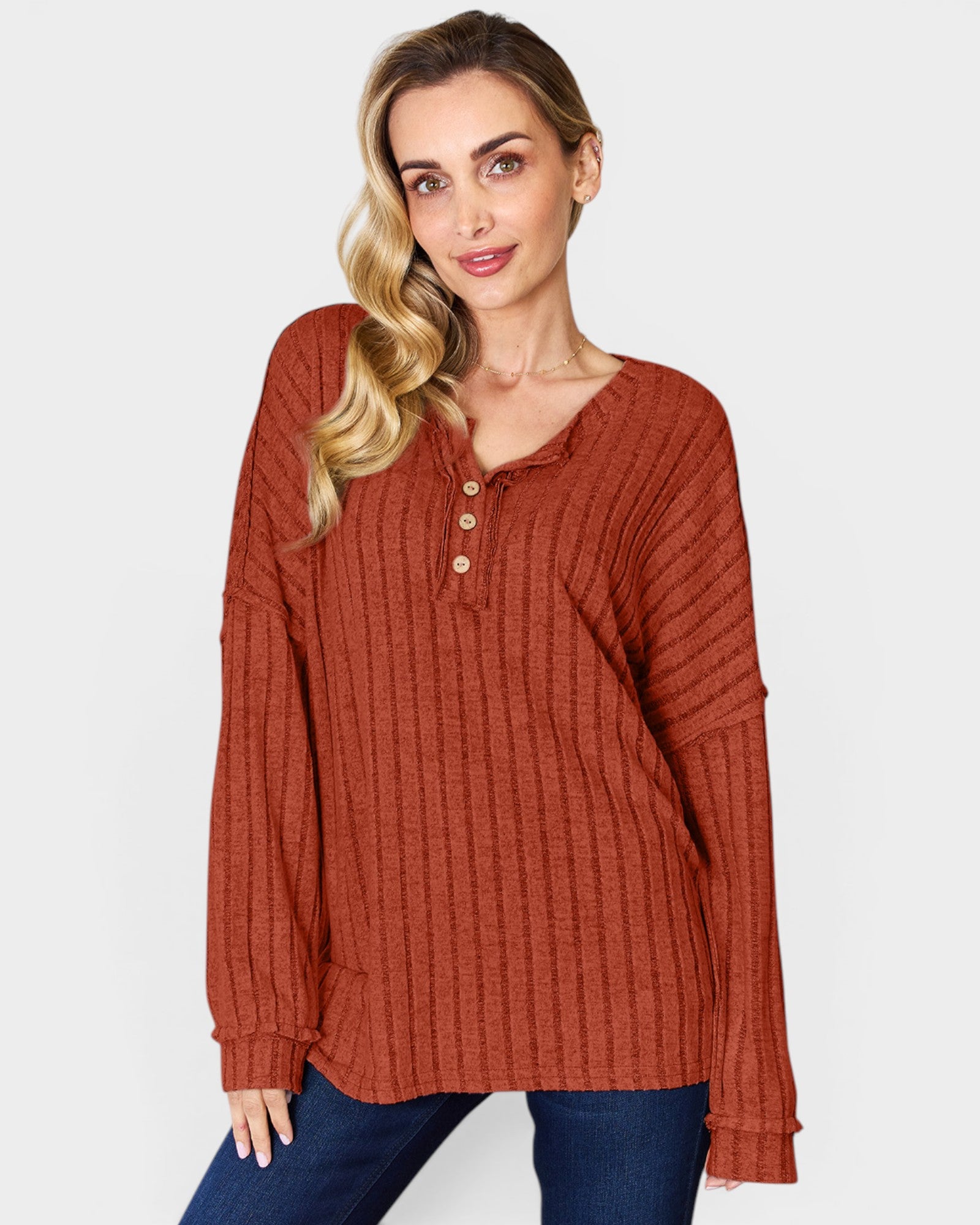 Woman wearing a rust-colored long-sleeve top on a plain background