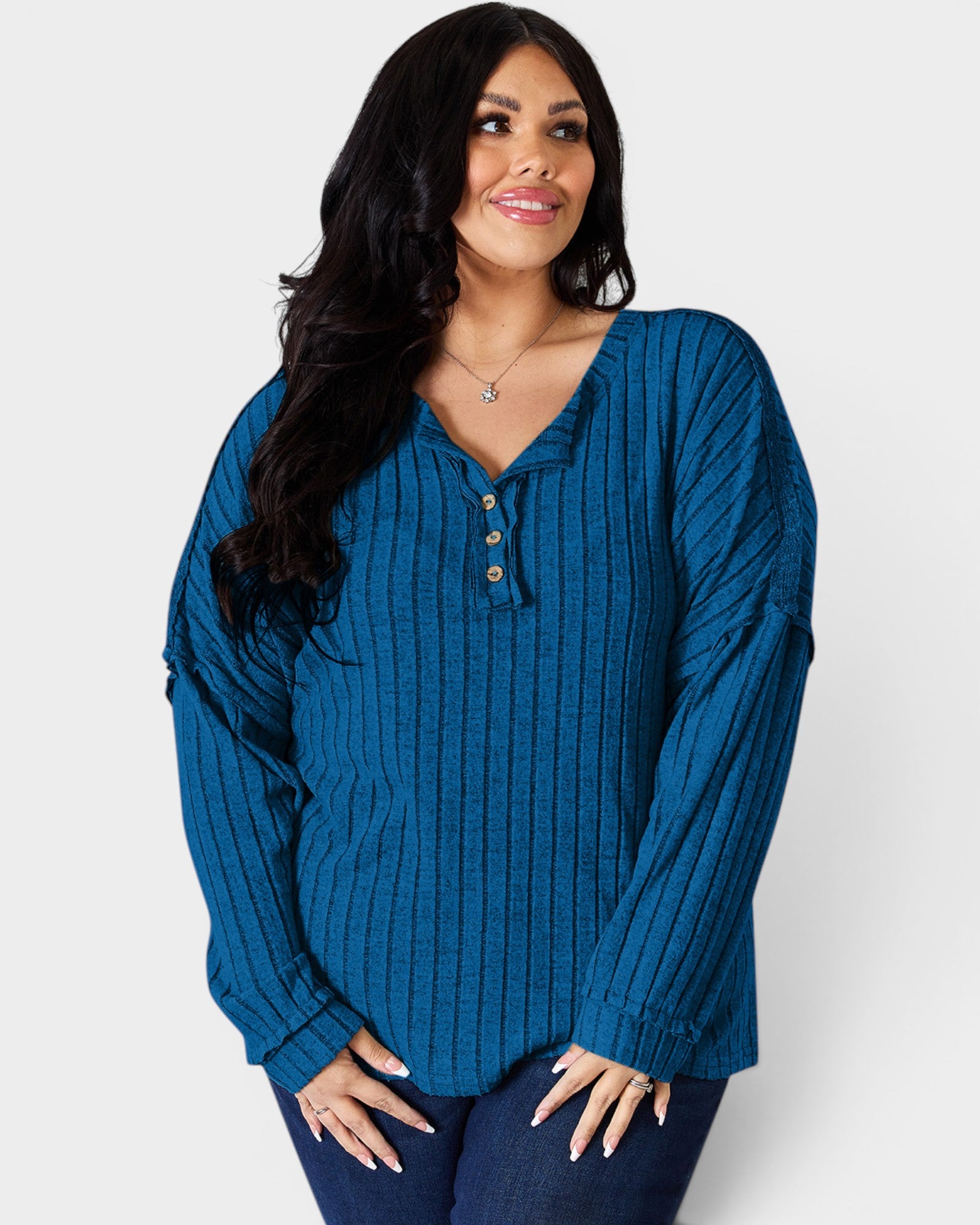 Woman wearing a blue ribbed long-sleeve top against a white background