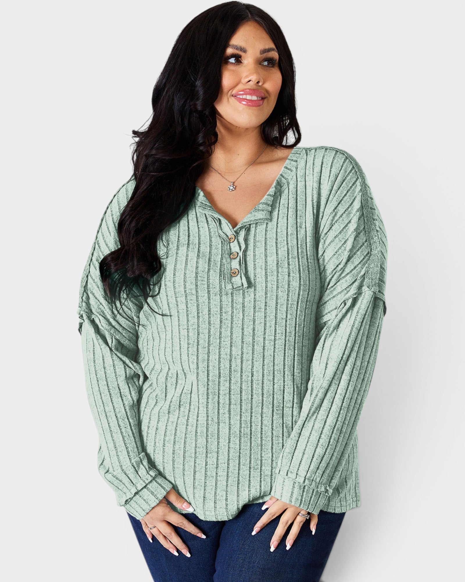 Woman wearing a green ribbed long-sleeve top against a white background