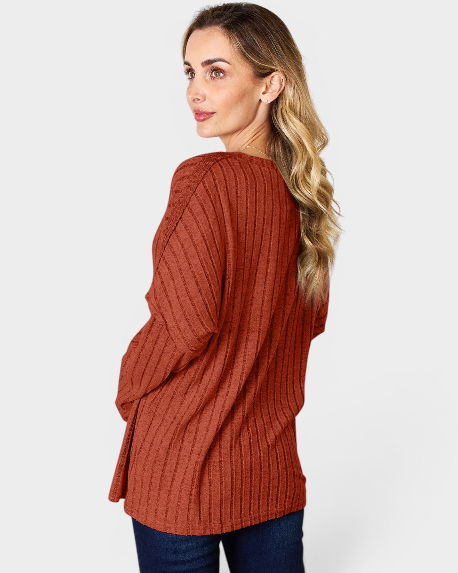 Woman wearing a rust-colored ribbed sweater on a white background