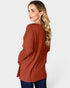 Woman wearing a rust-colored ribbed sweater on a white background