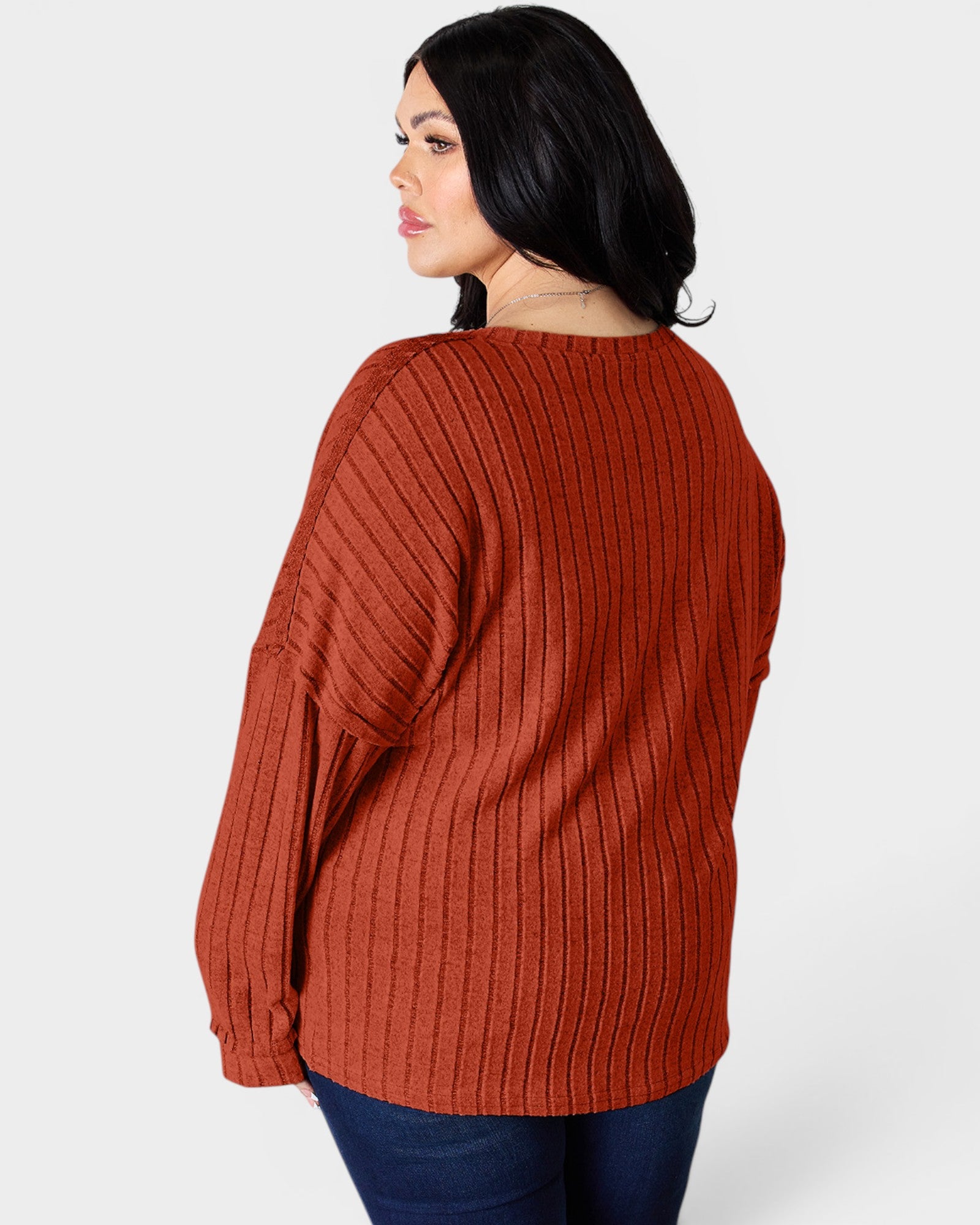 Person wearing a rust-colored ribbed sweater on a white background
