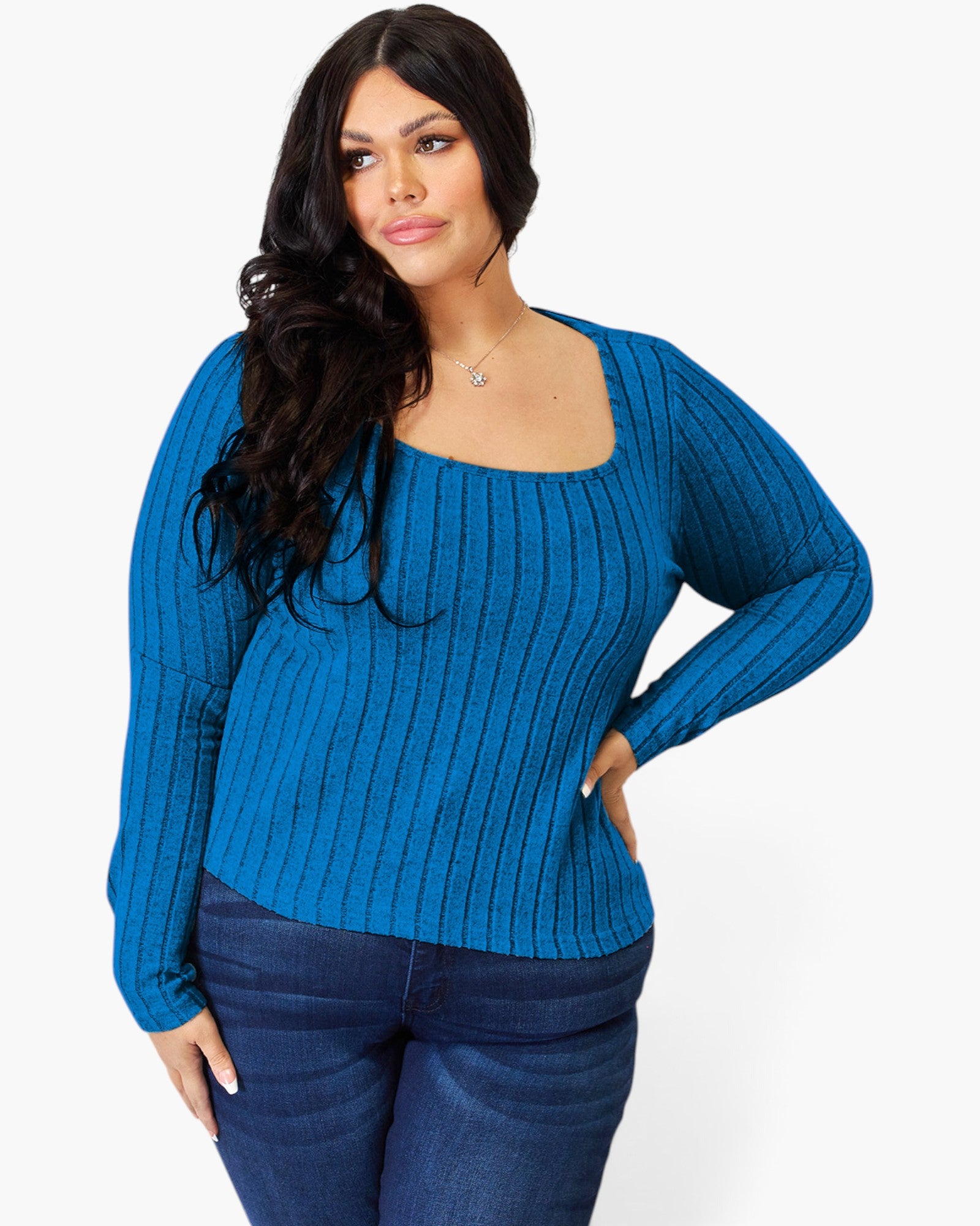 A woman modeling a bright blue ribbed knit sweater with a square neckline and long sleeves, paired with dark blue jeans, against a plain light gray background.
