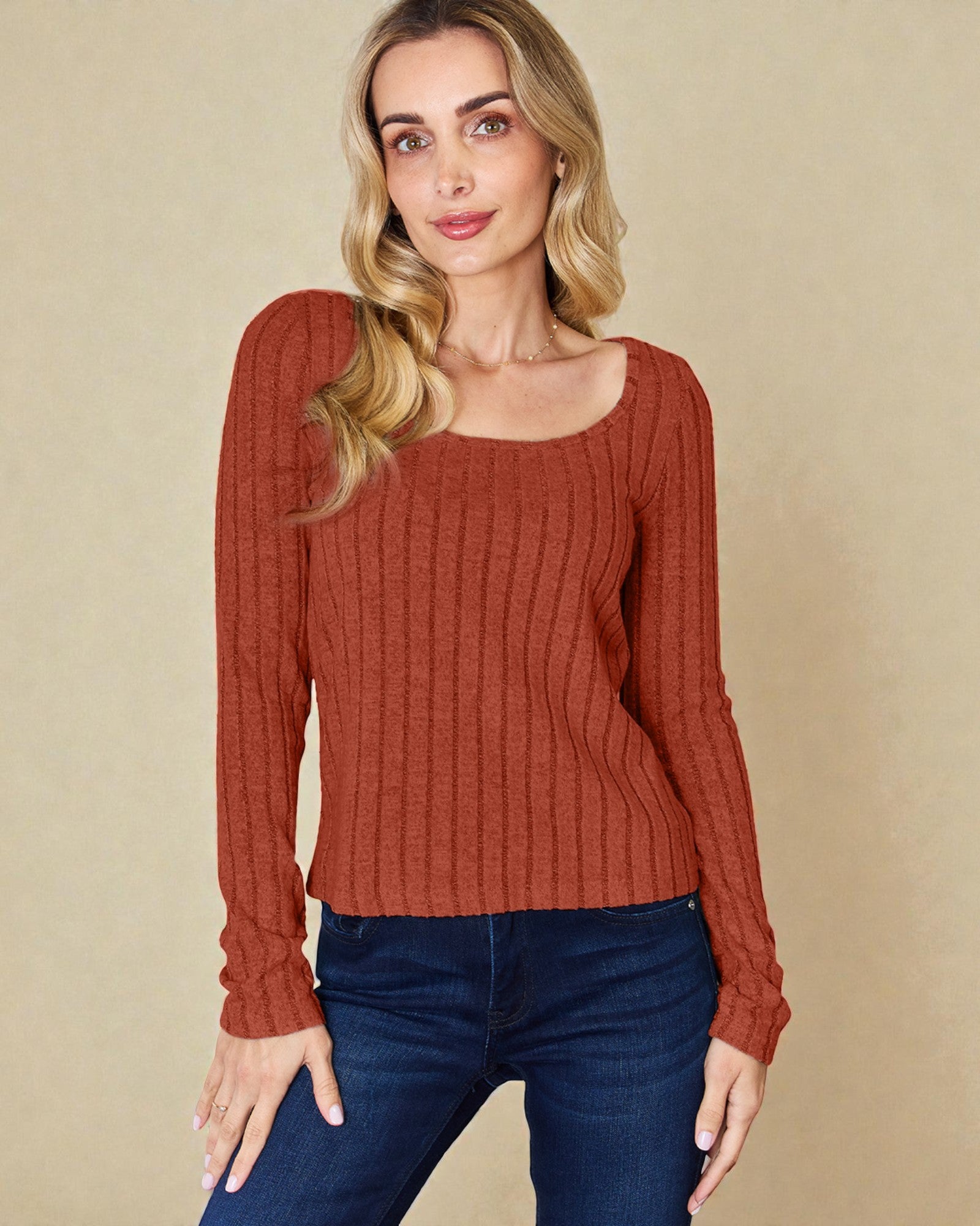 Woman wearing a rust-colored sweater against a beige background