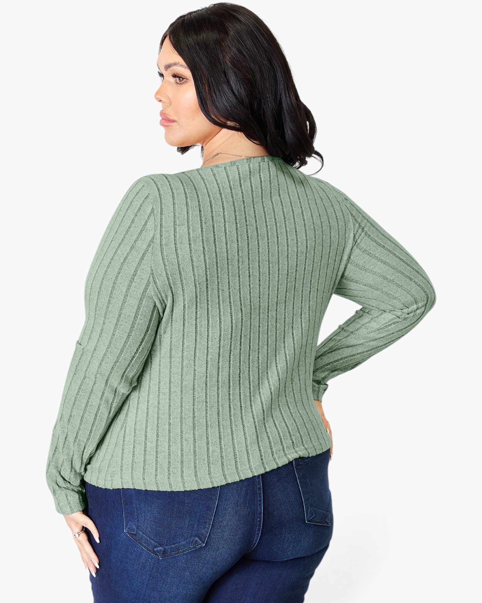 A woman shown from the back wearing a sage green ribbed knit sweater and dark blue jeans against a plain white background.