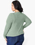 A woman shown from the back wearing a sage green ribbed knit sweater and dark blue jeans against a plain white background.
