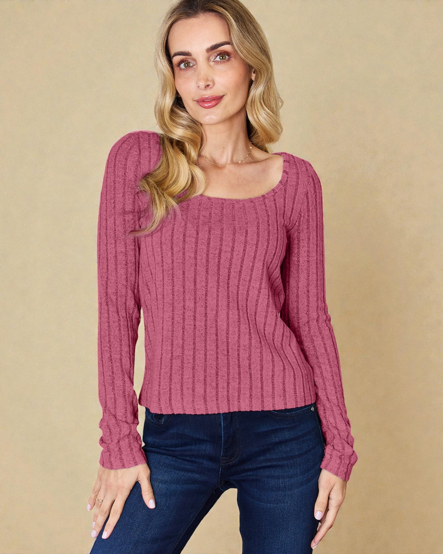 Woman wearing a pink ribbed sweater against a beige background