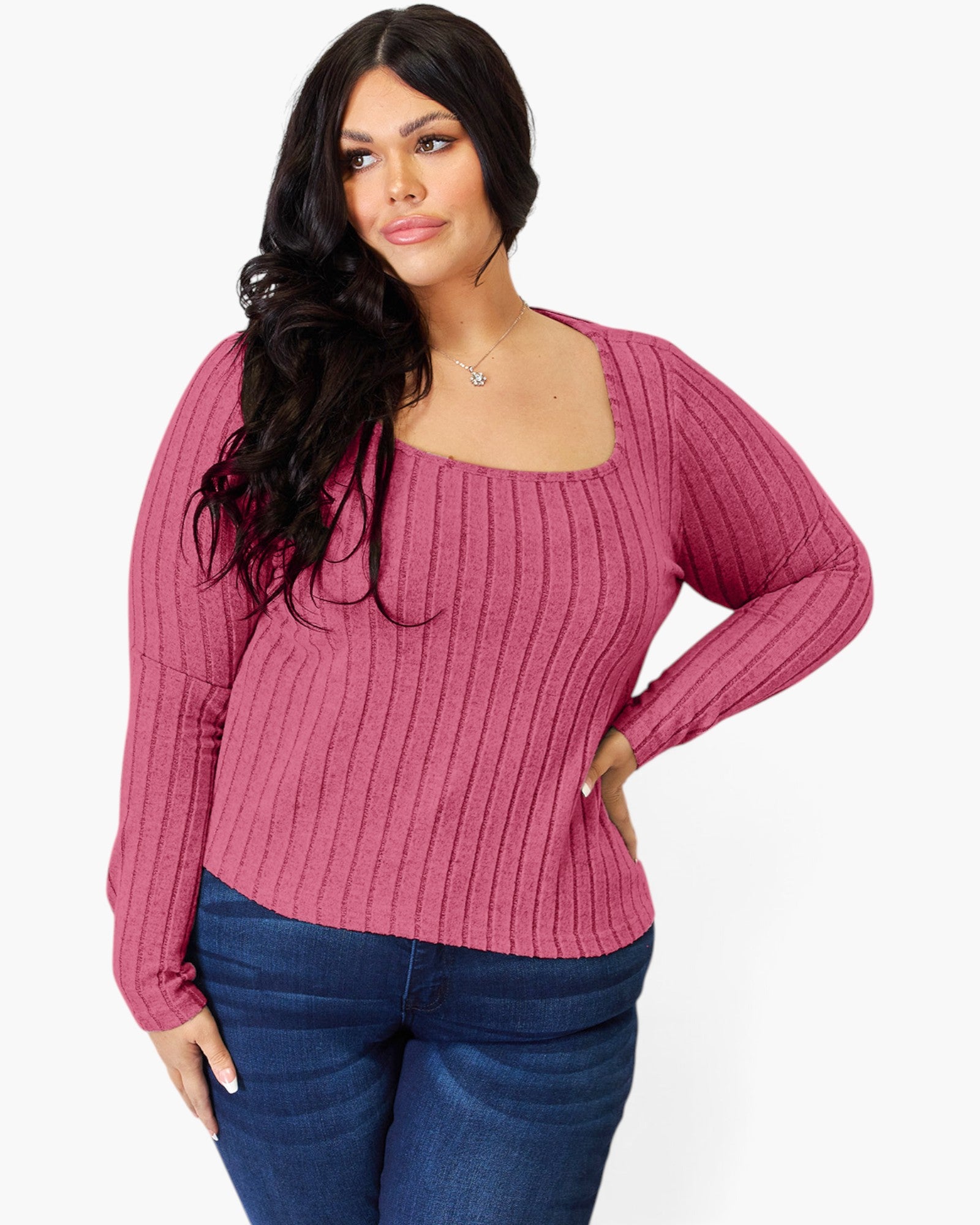 A woman modeling a ribbed knit long-sleeve top in dusty rose pink with a square neckline, paired with dark blue jeans, against a plain white background.
