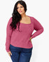 A woman modeling a ribbed knit long-sleeve top in dusty rose pink with a square neckline, paired with dark blue jeans, against a plain white background.