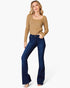 A woman modeling a tan ribbed knit scoop-neck sweater and dark blue flare jeans against a plain white background.