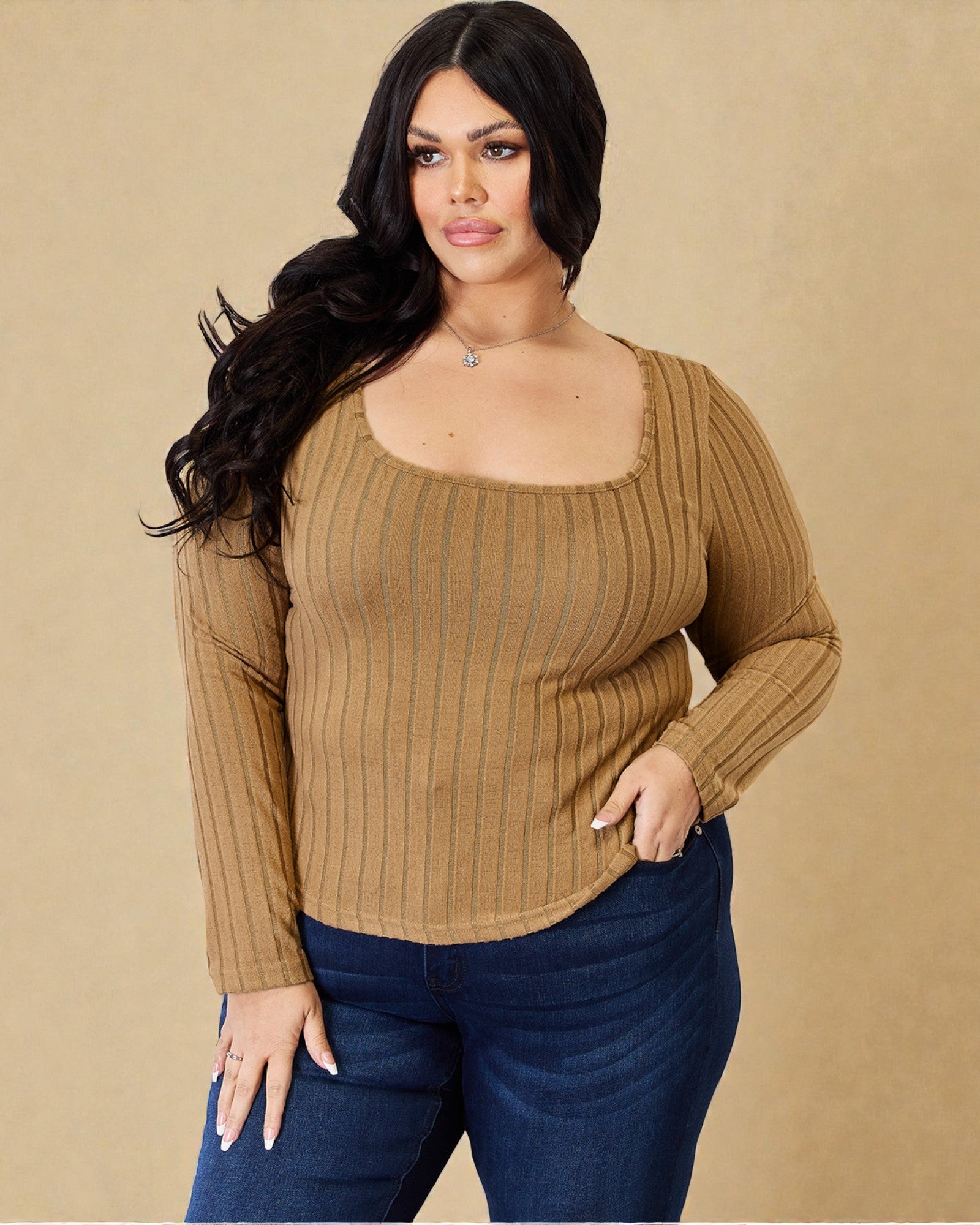Woman wearing a brown ribbed sweater and blue jeans against a beige background