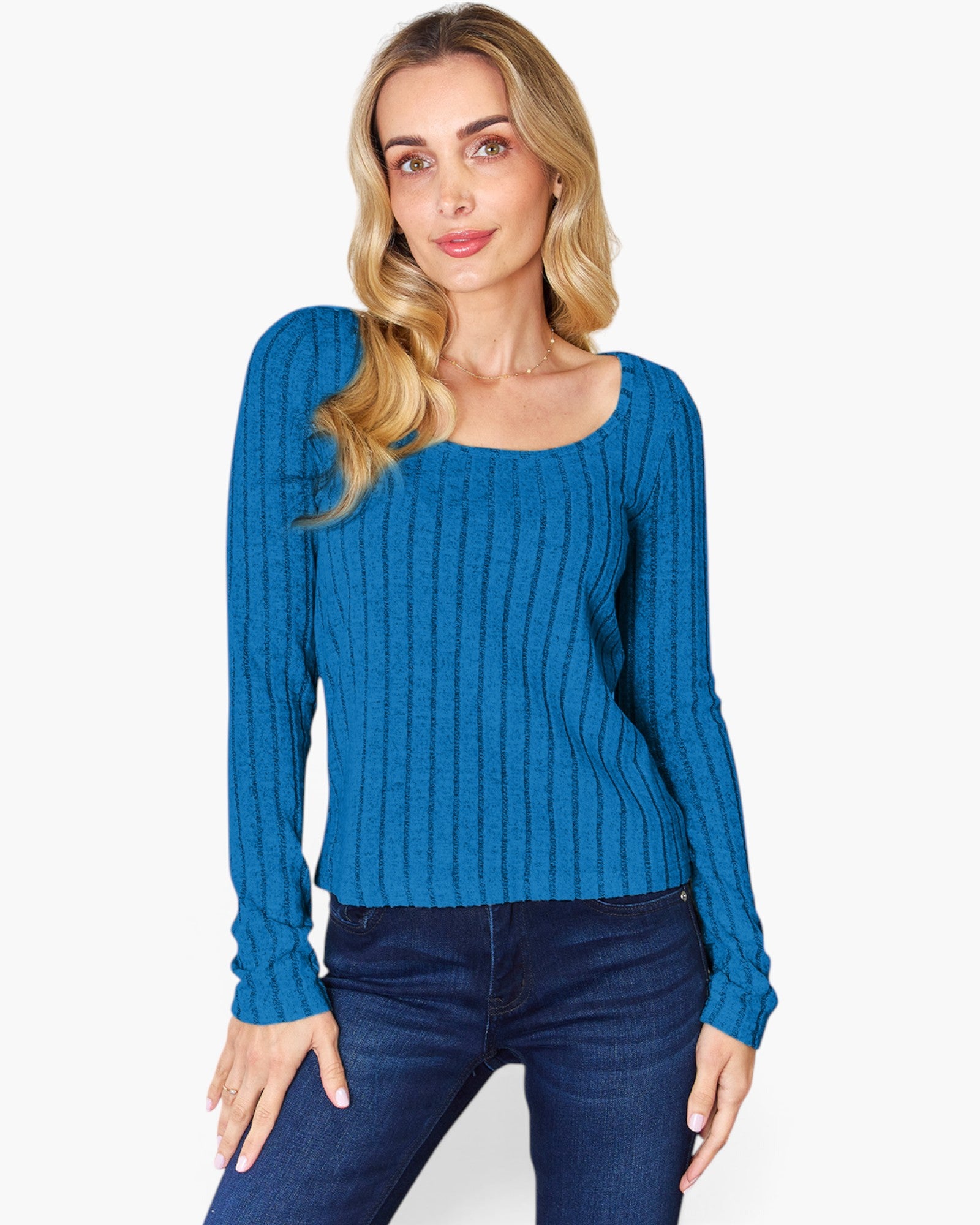 A woman modeling a blue ribbed knit long-sleeve top with a scoop neckline, paired with dark blue jeans, against a plain light gray background.