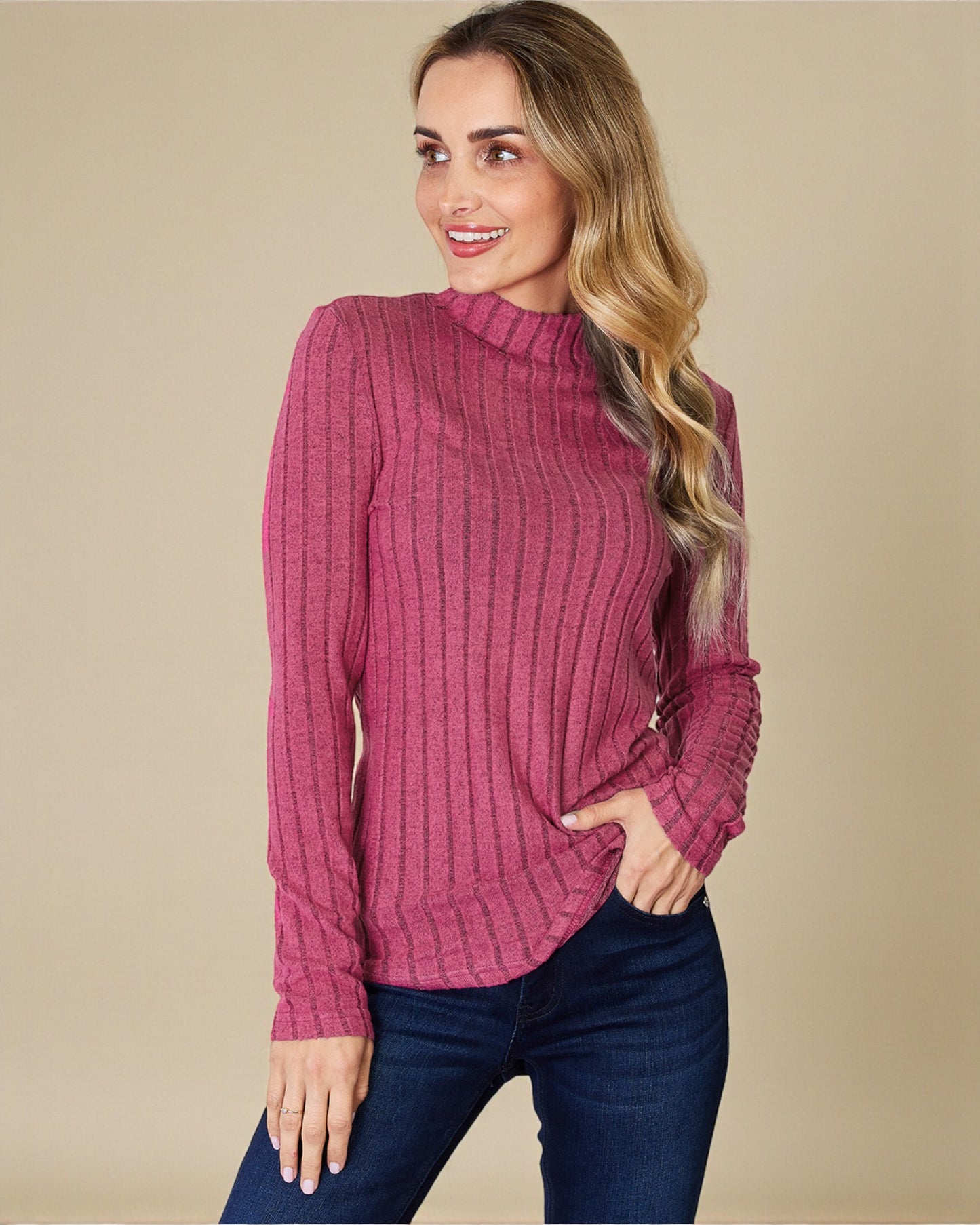 Woman wearing a pink ribbed sweater against a beige background