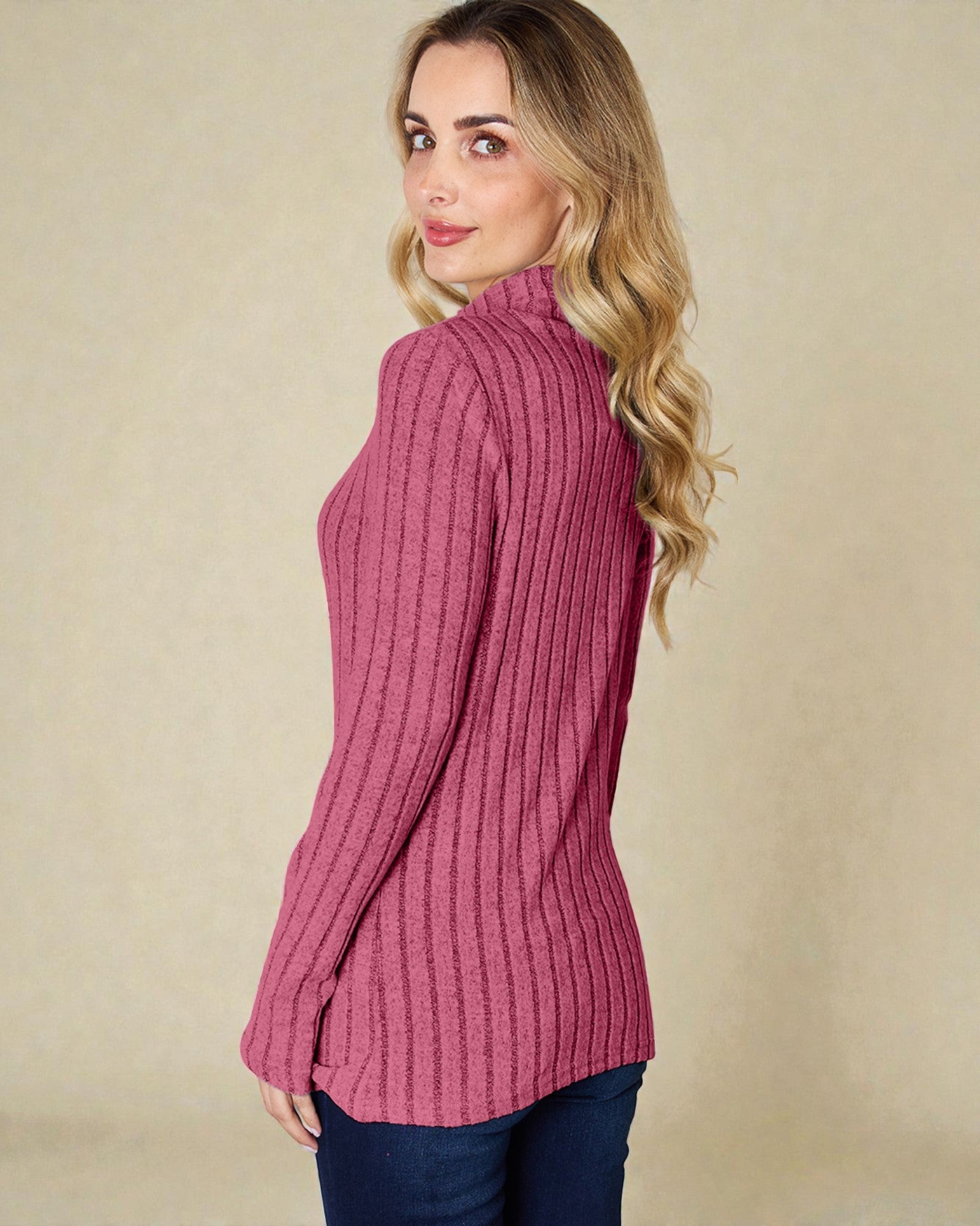 Woman wearing a pink ribbed sweater against a beige background