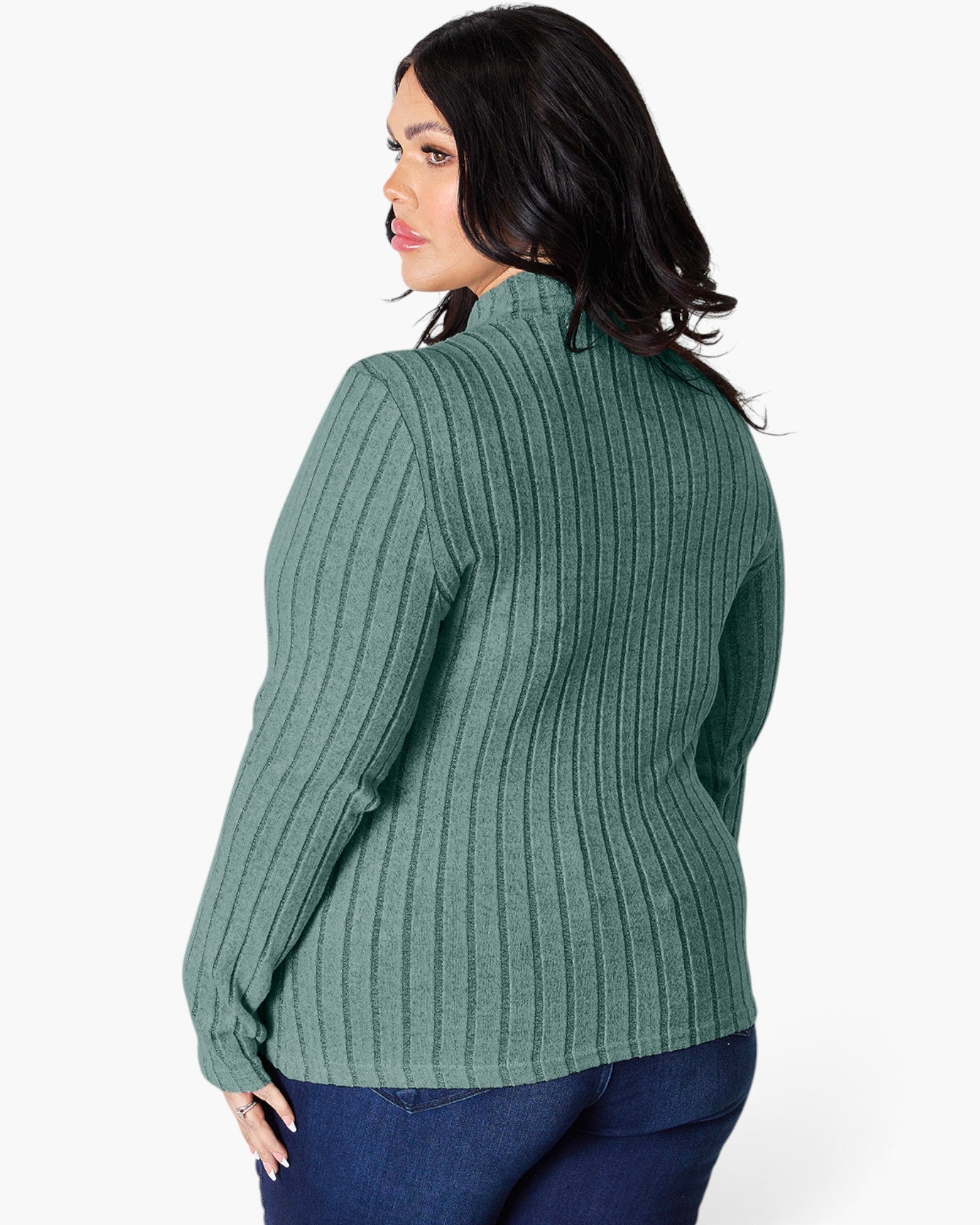 A woman shown from the back wearing a sage green ribbed knit sweater and dark blue jeans against a plain white studio background.