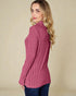 Woman wearing a pink ribbed sweater against a beige background