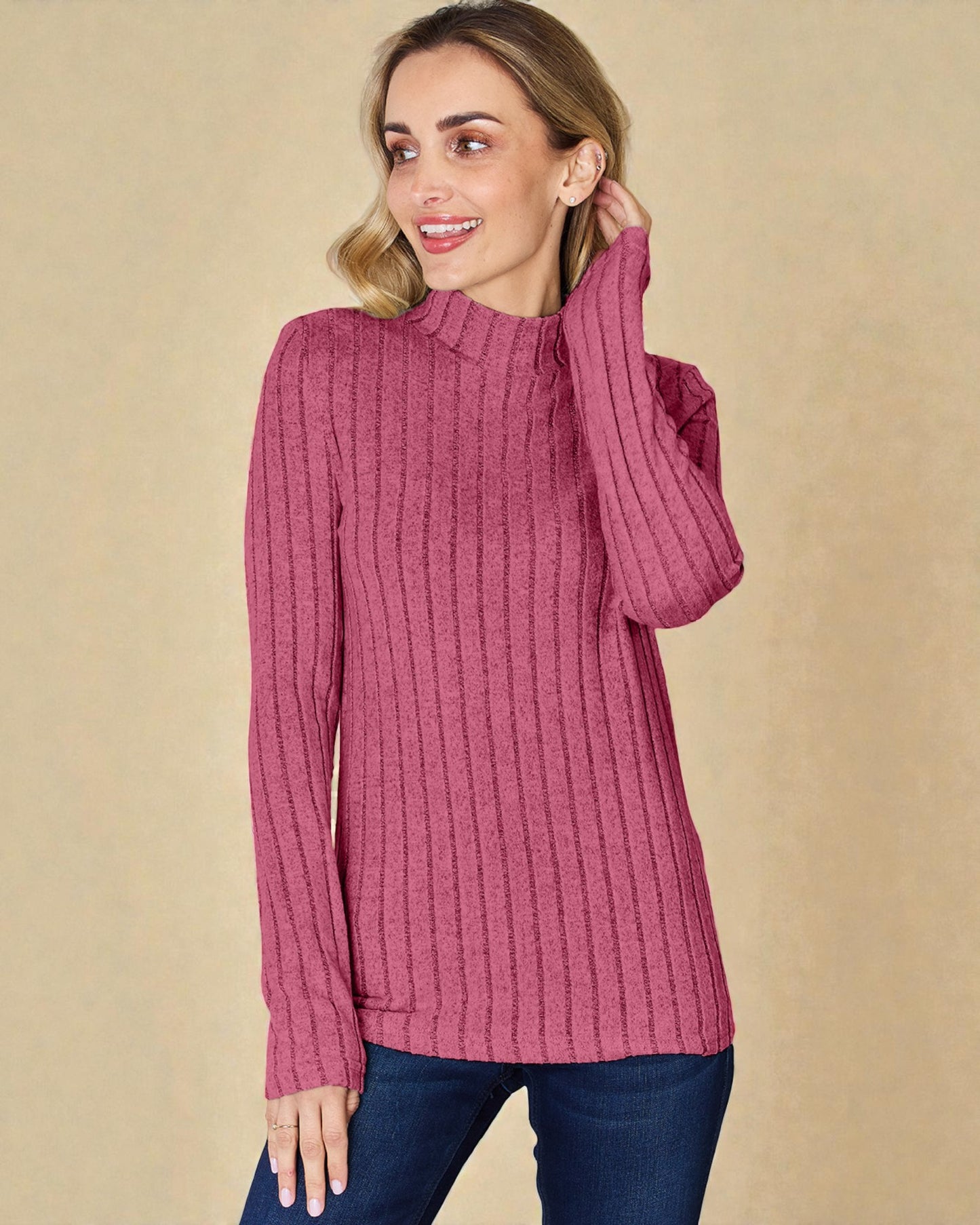 Woman wearing a pink ribbed sweater against a beige background