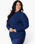 A woman modeling a navy blue ribbed mock neck sweater against a plain white background.