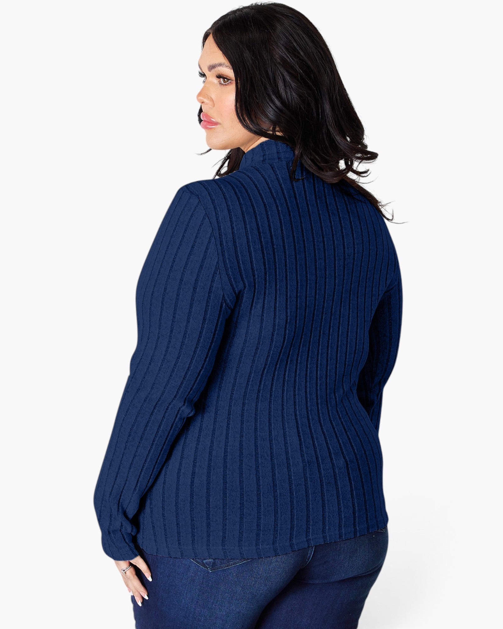A woman shown from the back wearing a navy blue ribbed knit sweater and dark blue jeans against a plain white studio background.