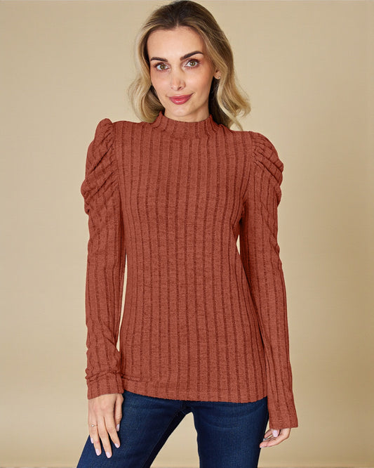 Woman wearing a rust-colored ribbed sweater against a beige background