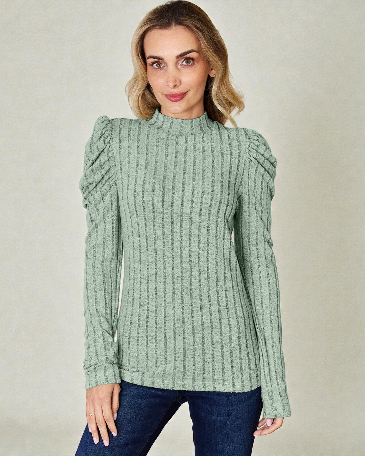 Woman wearing a green ribbed sweater against a plain background