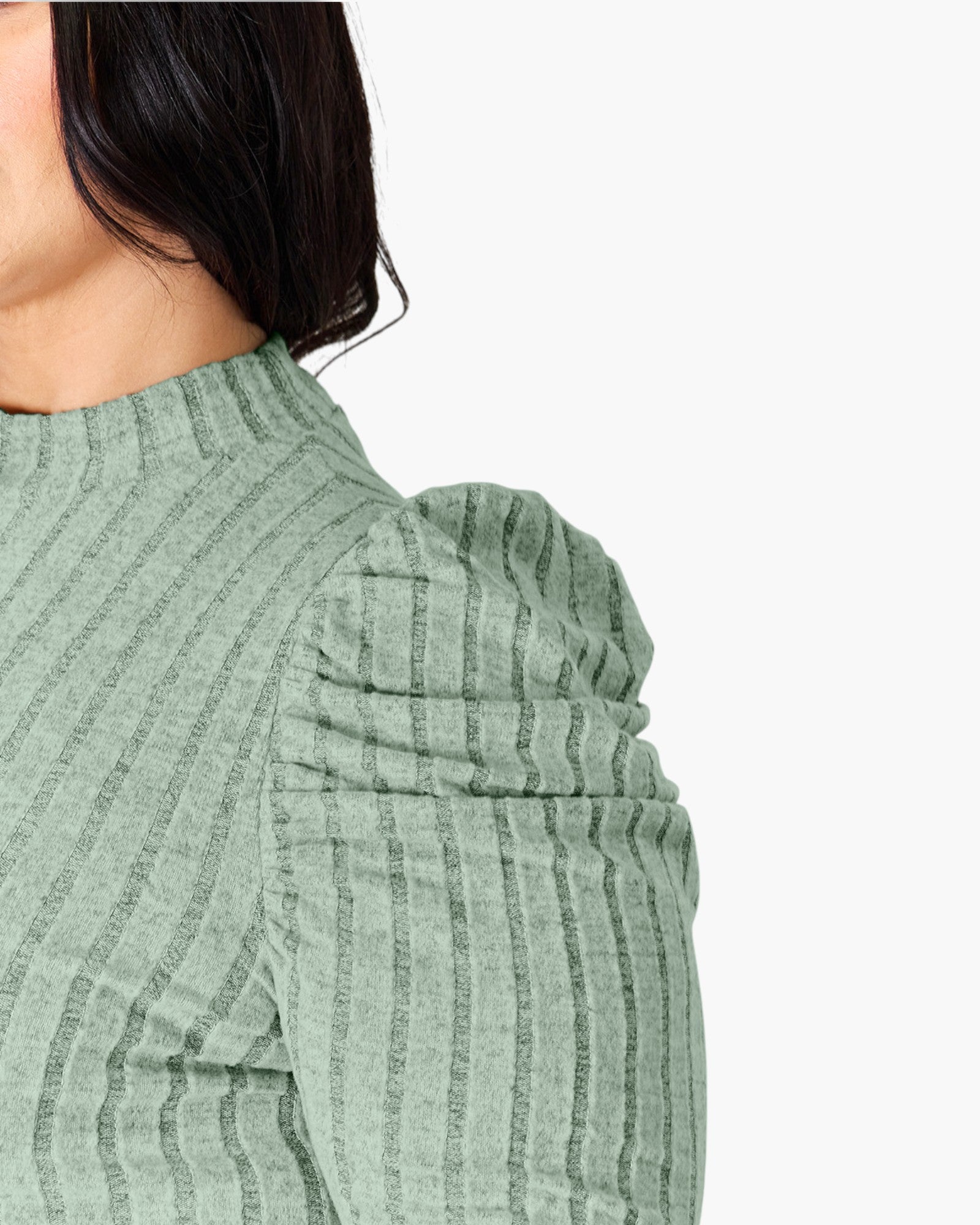 Close-up of a model wearing a sage green ribbed knit top with puffed shoulders against a plain white background.