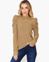 A woman wearing a camel brown ribbed knit mock neck top with dramatic puffed sleeves, paired with dark blue jeans, against a plain white background.